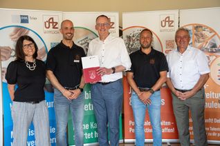 Wirtschaftsminister Michael Ebling (Mitte) übergibt den Förderbescheid des Landes Rheinland-Pfalz an das ÜAZ Wittlich. Mit dabei sind (von links) Teamleiterin Pia Debald, ÜAZ-Geschäftsführer Benjamin Uhl, Teamleiter Peter Feyen und Kreisbeigeordneter Achim Zender.