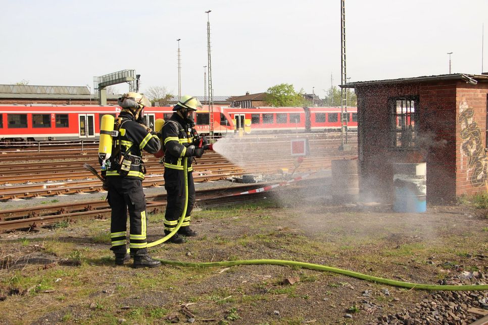 Zwei Feuerwehrleute bei Löscharbeiten auf dem Bahnhofsgelände.