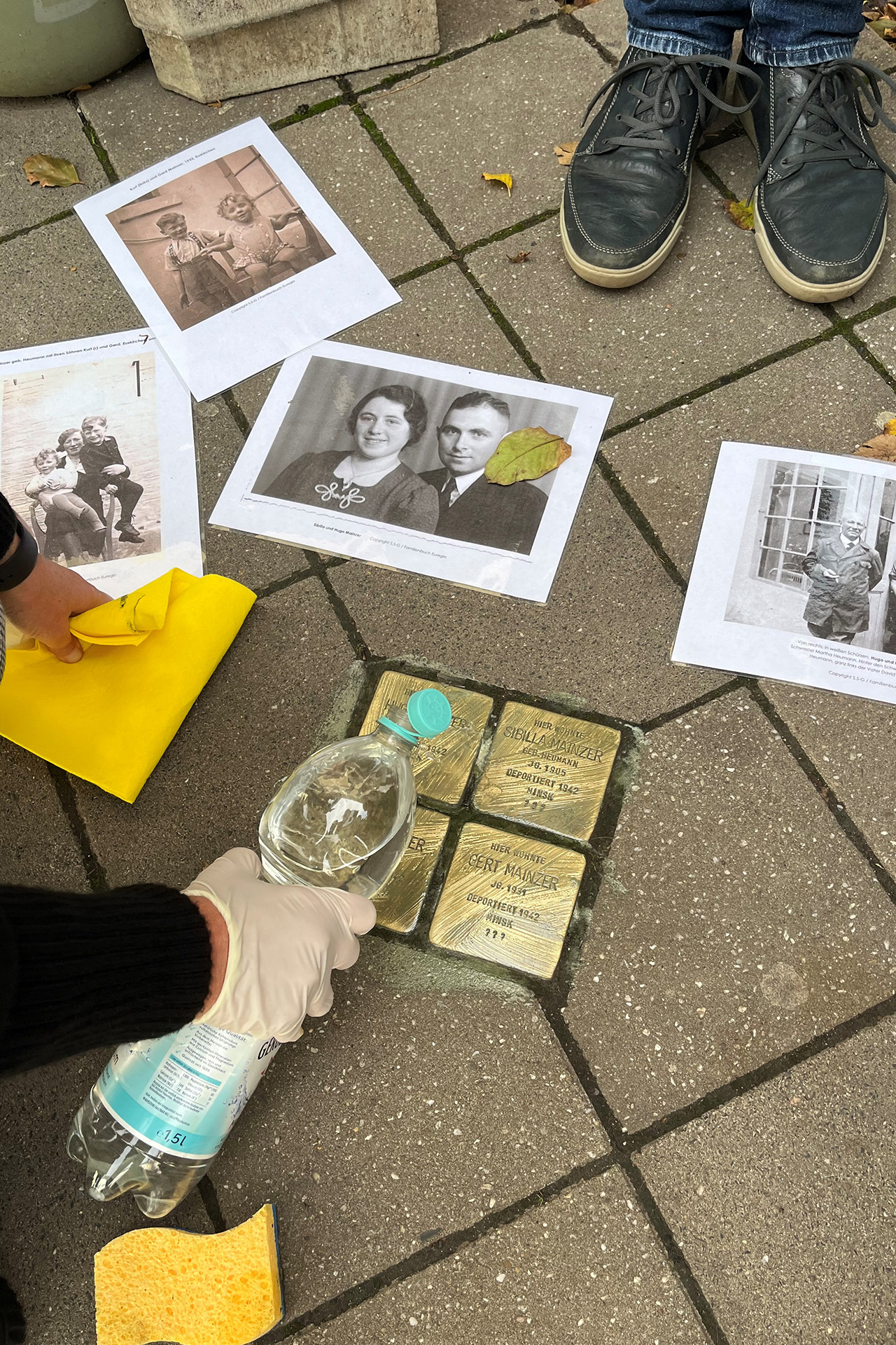 Den Stolpersteinen hat Roland Kuhlen mit Bildern der Opfer ein Gesicht gegeben, während die Messingtafel in Erinnerung an die Familie Mainzer von zugewanderten Menschen poliert werden. Foto: Roland Kuhlen/pp/Agentur ProfiPress