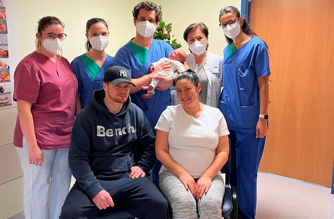 Vorne sitzend die jungen Eltern Steven Smith und Sabrina Artavia-Jungblut, stehend v.l. Hebamme Ann-Kathrin Fels, Assistenzärztin Nora Strack, Assistenzarzt Felipe Bejar-Recalde mit dem Neujahrsbaby Jake-Dylan, Chefärztin Izampella Papadopoulou und Assistenzärztin Inara Bayramova.