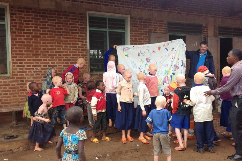 Tolles Ereignis: Martin Krings (r.) übergab den Kindern an der Albinoschule ein Tuch der Konzener Grundschüler.