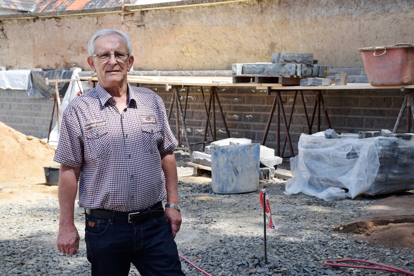 Hinter Ortsvorsteher Rolf Jaeck wird gerade die in die Jahre gekommene Mauer aufgehübscht. Voraussichtlich Ende Juli soll der Arenbergplatz als „attraktiver Platz im Herzen von Kommern“ wieder bezugsfertig sein. Foto: Kirsten Röder/pp/Agentur ProfiPress