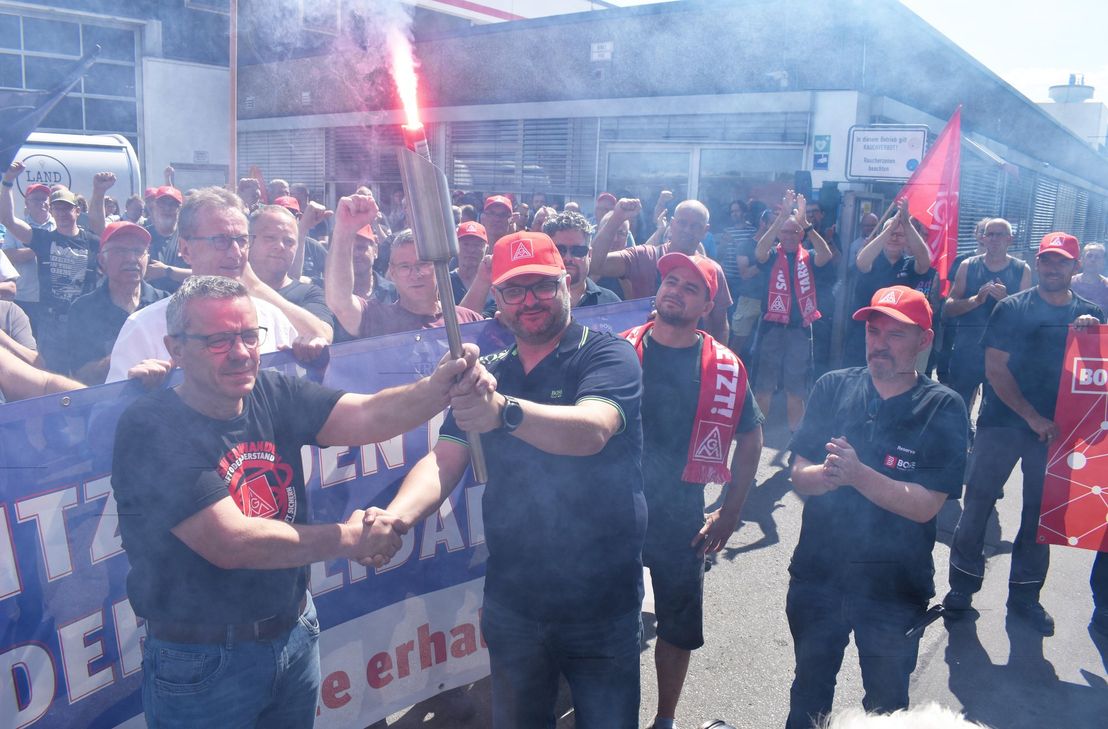 Nach der erfolgreichen Verhandlung gibt Marco Friedrich (Betriebsrat Boge, Mitte) die "Flamme der Solidarität" an Musashi-Kollegen weiter.
