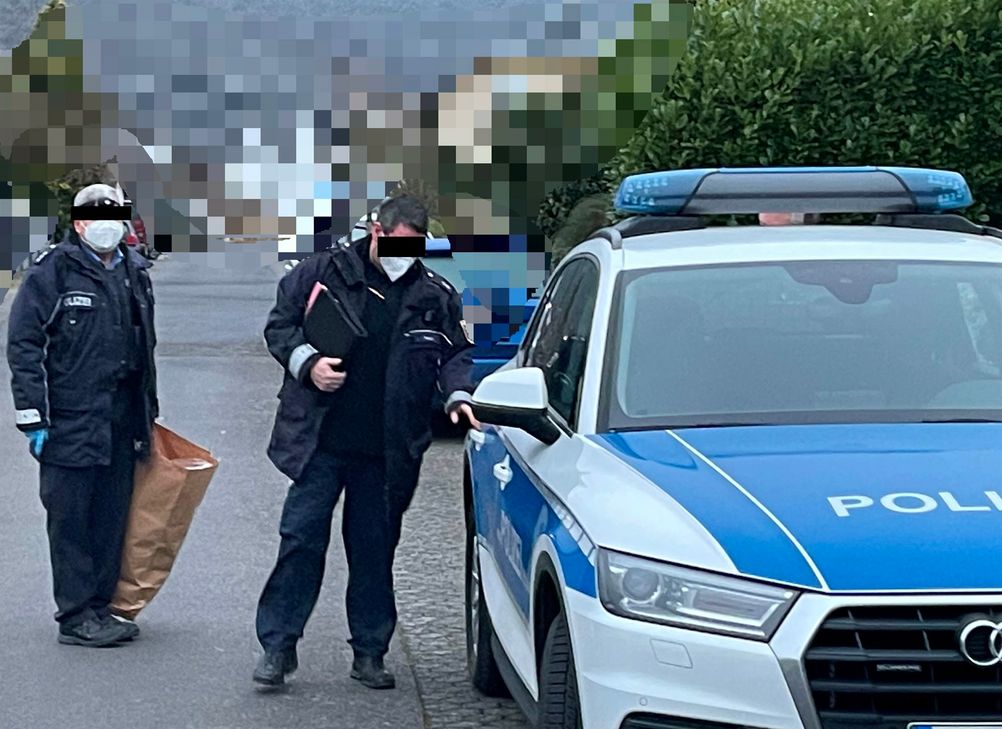 Nach der Durchsuchung tragen Polizeibeamte sichergestellte Beweismittel in den Streifenwagen. Zuvor hatten sie 46 Minuten das Wohnhaus des Verdächtigen durchsucht.
