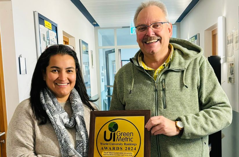 Nachhaltigkeitsbeauftragter Prof. Dr. Klaus Helling nimmt am UCB stolz die Plakette von Jackeline Martinez entgegen.