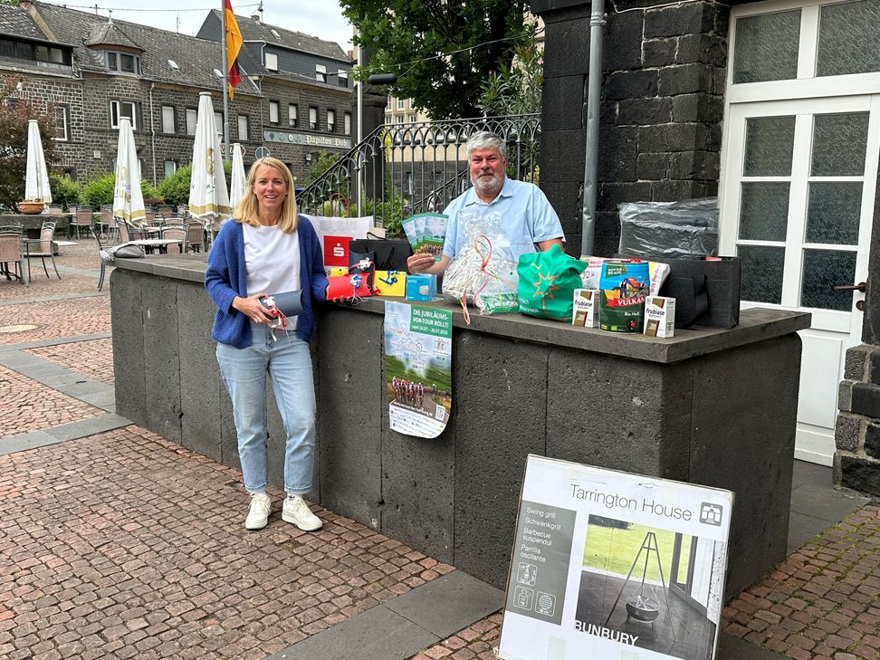 Eva Ivo und Mendigs Stadtbürgermeister Achim Grün präsentieren einen kleinen Querschnitt der Preise, die bei der Tombola zugunsten der „VOR-TOUR der Hoffnung“ im Gewinntopf sind.