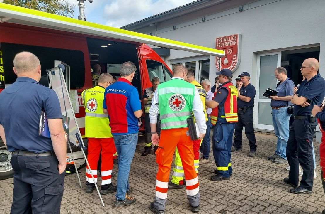 Am Gerätehaus der Freiwilligen Feuerwehr Kirchzell findet eine Lagebesprechung statt.