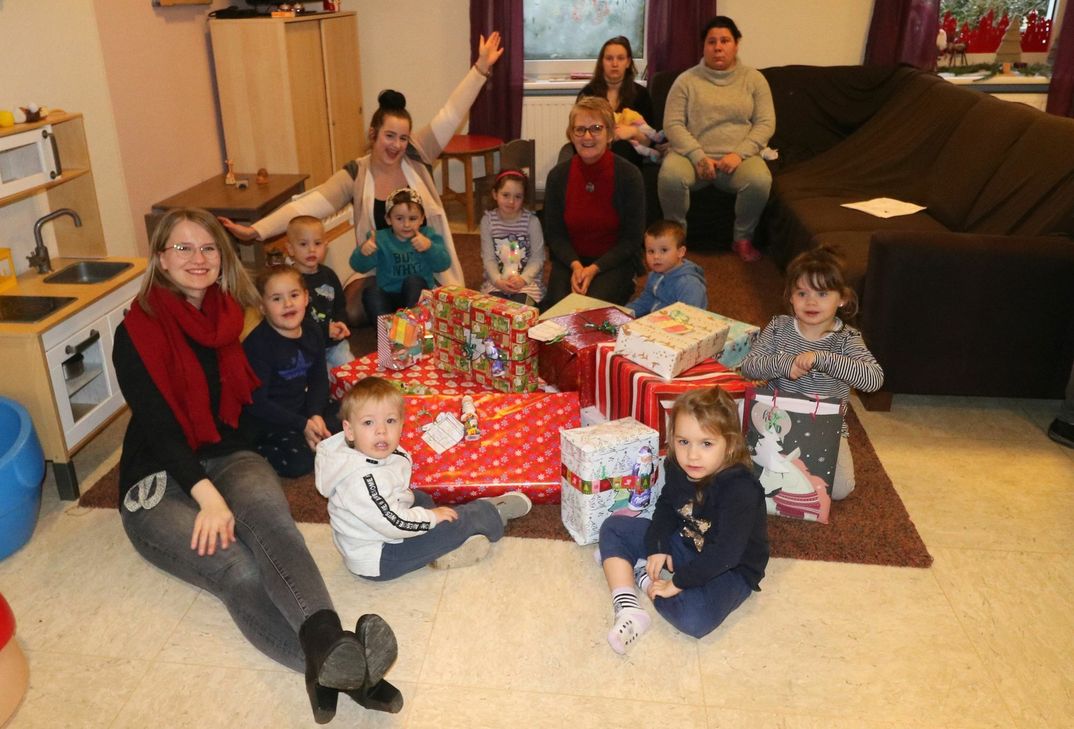 Die Mitarbeiterinnen der Evangelischen Kinder-, Jugend- und Familienhilfe Schmiedel, Gabi Hamann und Katharina Schaum, gemeinsam mit einigen Kindern und Eltern kurz vor der Geschenkevergabe.