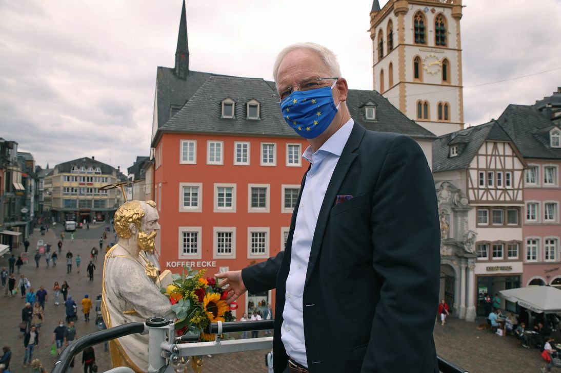 OB und Stadtpatron sind sich ganz nah: Wolfram Leibe hat der Petrusfigur auf dem Hauptmarkt den traditionellen Blumenstrauß in den Stadtfarben Gelb-Rot überreicht. Foto: Presseamt Trier