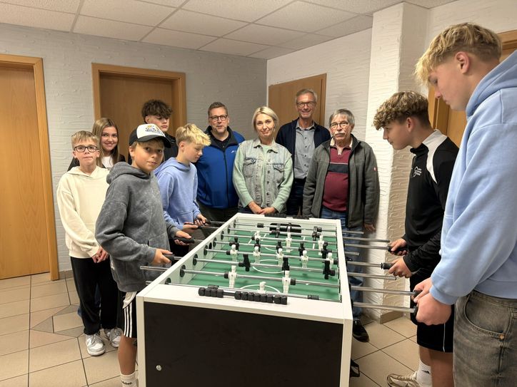 Jugendliche beim Tischkicker spielen sowie Initiatorin Olga Veresokin, Ortsbürgermeister Manuel Weber, Beigeordneter Bernhard Werle und OIE Vorstand Thomas Johann