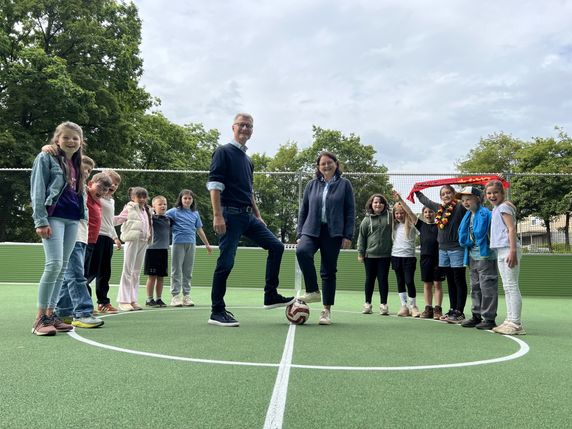 Bürgermeister Jan Lembach und Schulleiterin Mirjam Schmitz beim offiziellen Anstoß auf dem neuen Soccer-Court, der bei den Schülern der Grundschule Dahlem bestens ankommt - gerade in Zeiten der Fußball-WM.