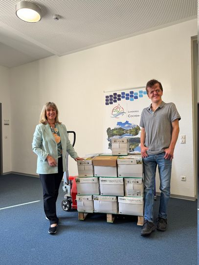 Landrätin Anke Beilstein übergibt 22 Kartons mit Kronkorken an Adrian Justen.