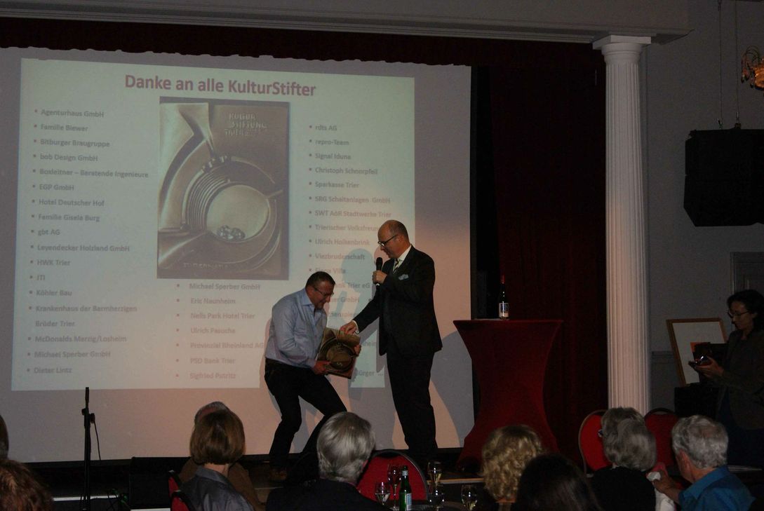 Eric Naunheim bekommt die schwere Stifterplatte überreicht. Die in Bronze gegossene Stifterplatte zeigt das Amphitheater mit zwei kämpfenden Gladiatoren. Foto: Schieke