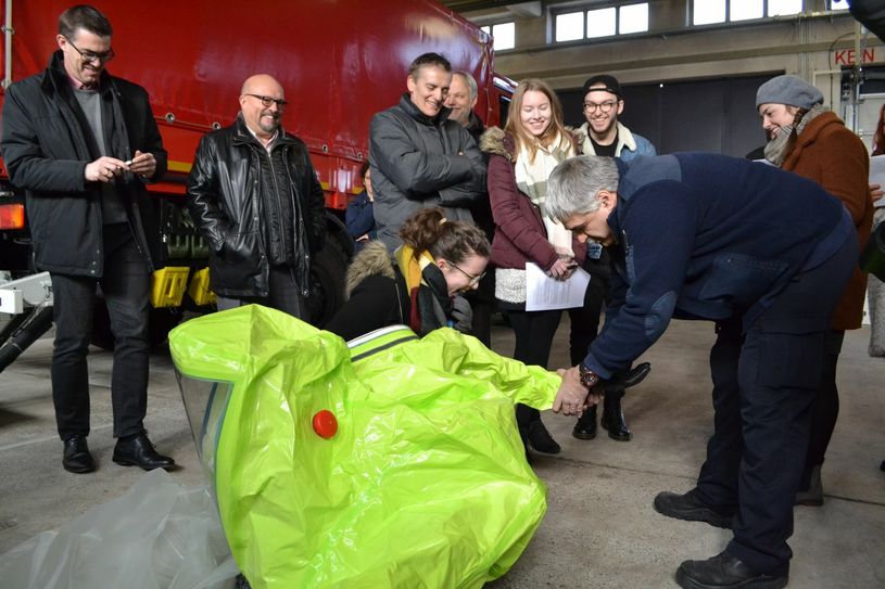 Gerd Uelpenich (r.) demonstrierte half den Abiturienten des Rhein-Gymnasiums zu spüren, wie schwer es ist, die Finger in den Handschuhen eines Schutzanzugs zu koordinieren. Foto: Mager