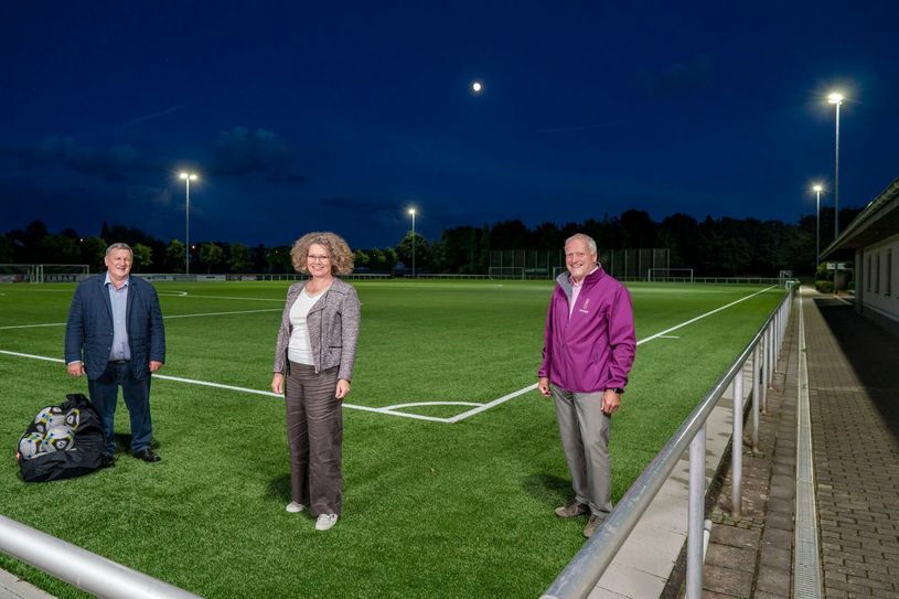 Der Vollmond strahlt mit dem Flutlicht am Weilerswister Sportzentrum um die Wette. Bürgermeisterin Anna-Katharina Horst und SSV-Vize-Vorsitzender Willi Rau (l.) freuen sich über die finanzielle Unterstützung durch innogy, hier vertreten durch Kommunalbetreuer Walfried Heinen. (Foto: innogy/Klaus Görgen)