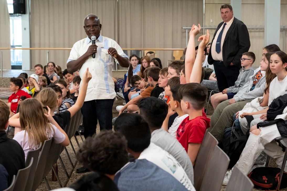 Zahlreiche Finger hoch: Die Schülerinnen und Schüler der Euskirchener Marienschule hatten etliche Fragen an die afrikanischen Gäste um Cesar Beogo. Auch Schulleiter Michael Mombaur hörte interessiert zu.
