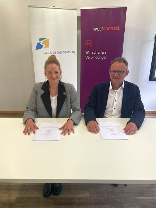 Anne Baedke, Abteilungsleiterin Westconnect, sowie Landrat Stefan Metzdorf beim Unterzeichnen des Kooperationsvertrages.