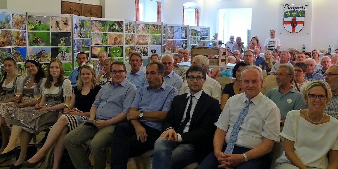 Interessiertes Publikum bei der Auszeichnung des Leuchtpunktes. Im Hintergrund ist die Fotoausstellung von Elmar Kohl und Theo Haart zu sehen.