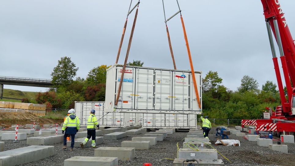 Die Batteriesspeicher werden auf die vorbereiteten Fundamente gesetzt.