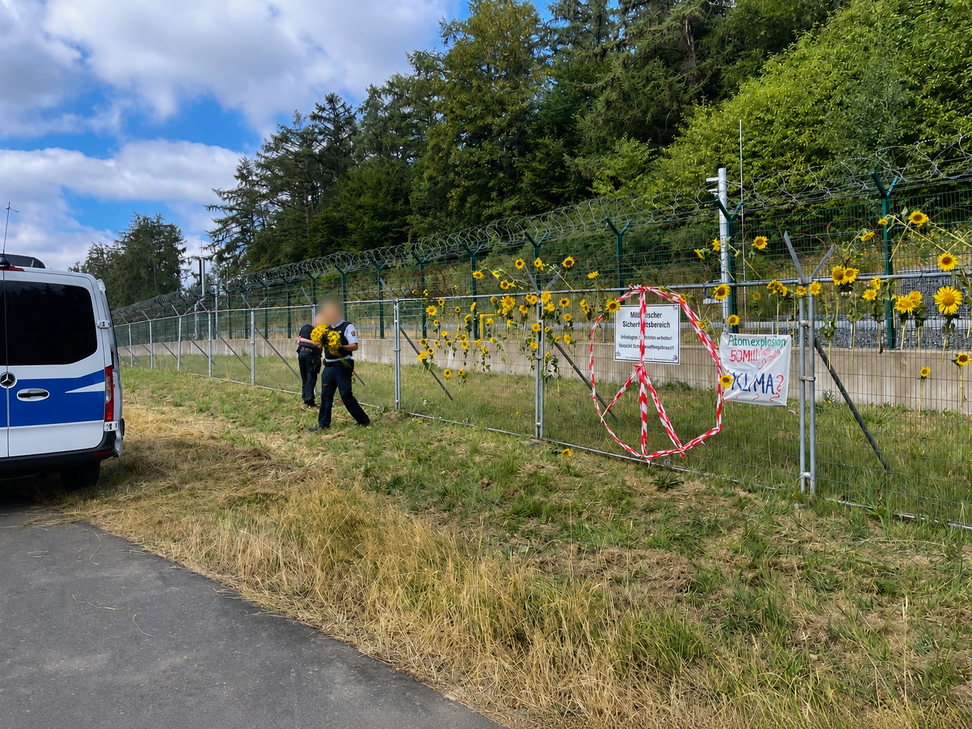 Polizeibeamte entfernen die Sonnenblumen, die von den Demonstranten am Zaun des Bundeswehrstandortes Büchel befestigt wurden.