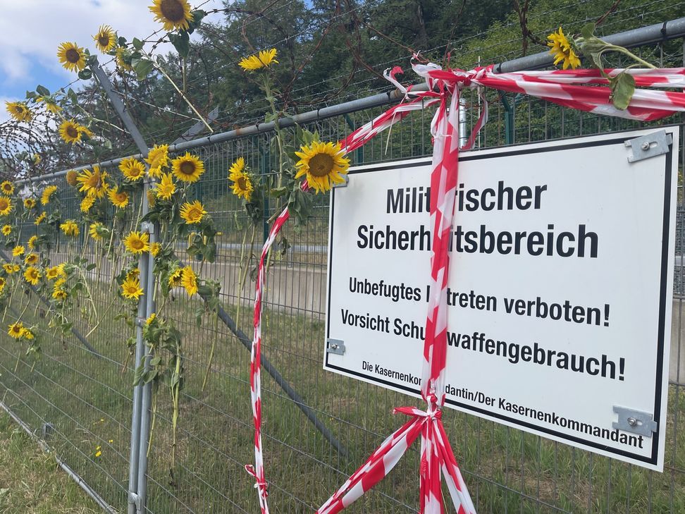 Polizeibeamte entfernen die Sonnenblumen, die von den Demonstranten am Zaun des Bundeswehrstandortes Büchel befestigt wurden.