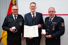 Innenminister Michael Ebling übergibt das Feuerwehr-Ehrenzeichen an Stefan Bohnenberger (l.) und Dirk Hargesheimer (r.).