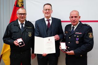 Innenminister Michael Ebling übergibt das Feuerwehr-Ehrenzeichen an Stefan Bohnenberger (l.) und Dirk Hargesheimer (r.).
