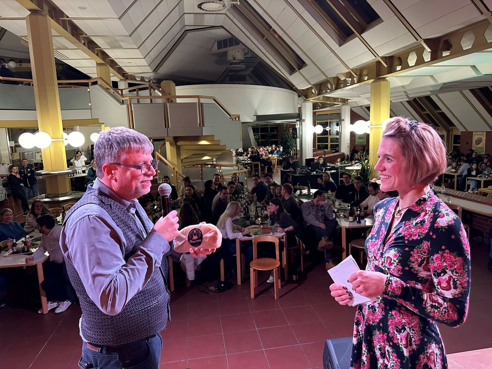 "Studiwerk Geschäftsführer Andreas Wagner bedankt sich mit einer symbolischen Klappschmier bei der wortgewandten Moderatorin Dr. Paula Kolz für die gelungene Präsentation von total lokal auf der Mensabühne."