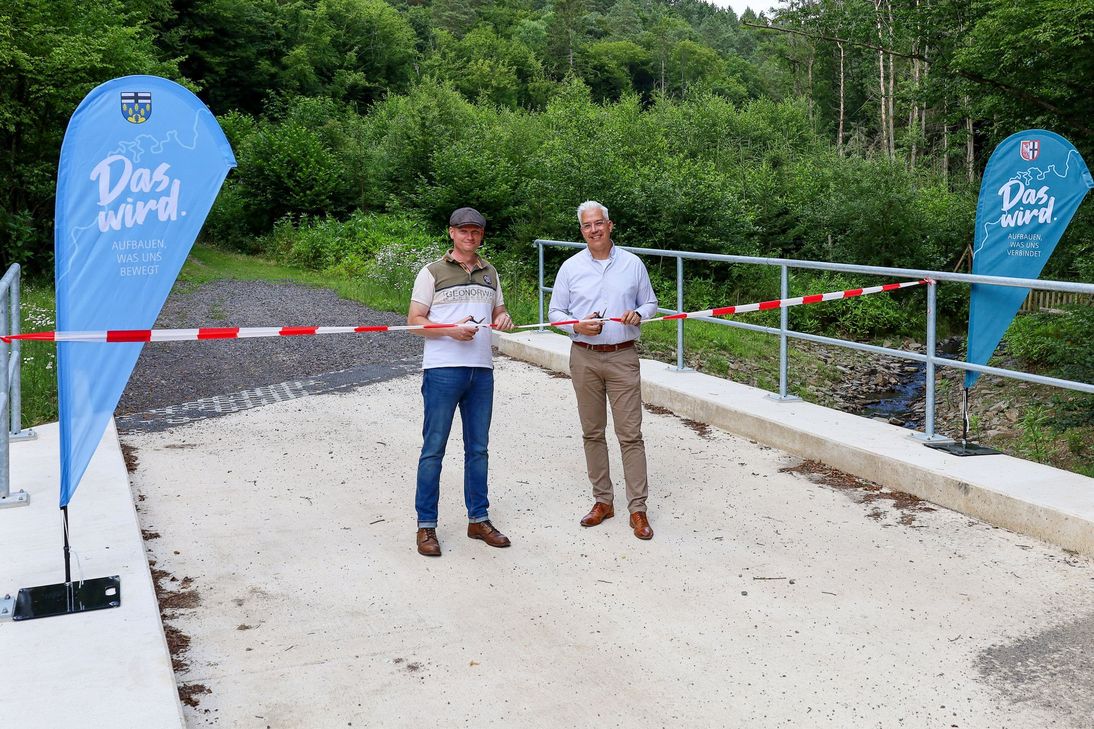 Mit dem symbolischen Akt der Durchschneidung des Absperrbandes gaben Ortsbürgermeister Benedikt Knoche (li.) und Dominik Gieler, Bürgermeister der Verbandsgemeinde Altenahr, die Vischelbachbrücke in Berg offiziell frei.