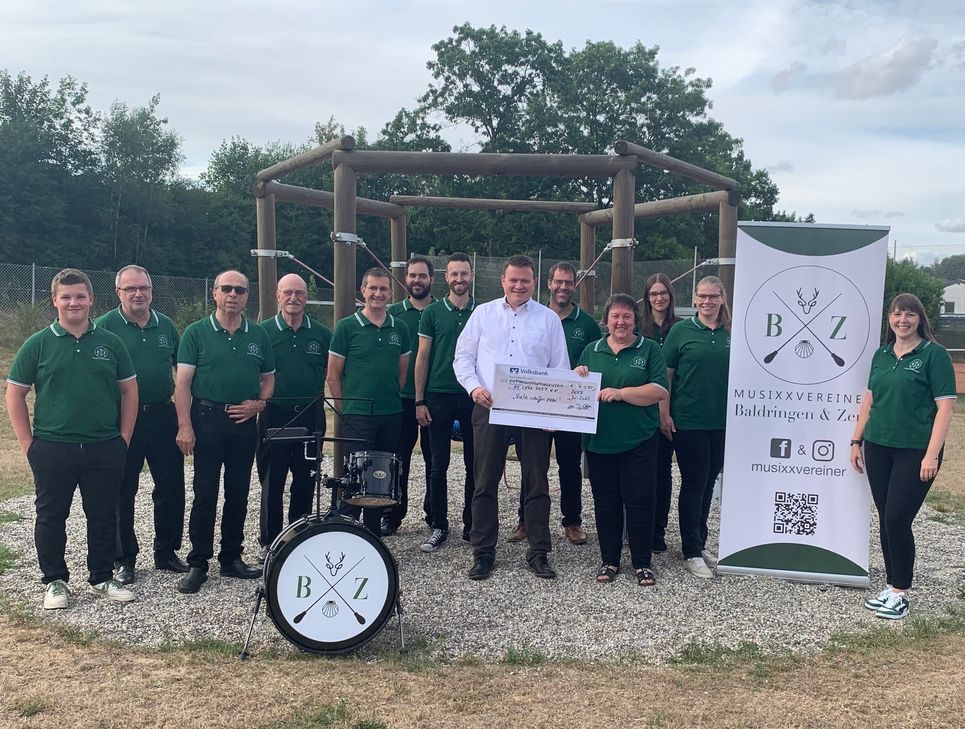 Regionaldirektor Dirk Müller überreicht den Check in Höhe von 4.045 Euro an Vertreter*innen der Musixxvereiner Baldringen &amp; Zerf .  Foto: Verein