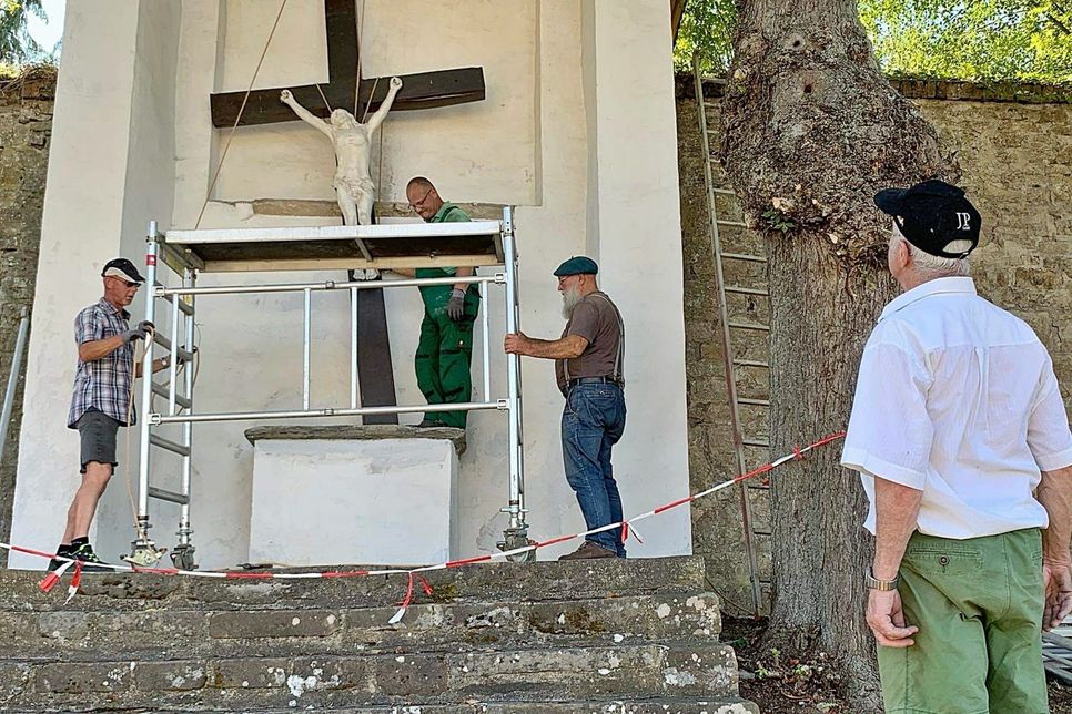 Mit viel Engagement und Muskelkraft tauschten diese Männer das marode Kreuz über dem Altar des Kalvarienbergs in Steinfeld aus. Foto: GdG Steinfeld