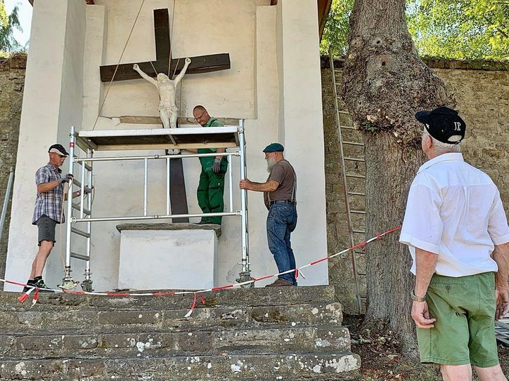 Mit viel Engagement und Muskelkraft tauschten diese Männer das marode Kreuz über dem Altar des Kalvarienbergs in Steinfeld aus. Foto: GdG Steinfeld