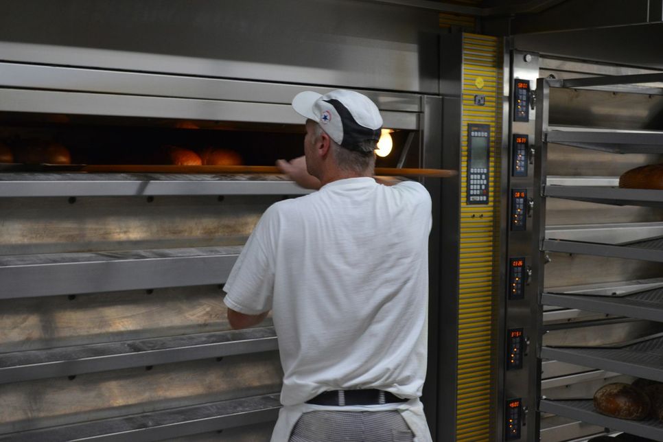Ein Blick in den Ofen: Ein Mitarbeiter der Bäckerei kontrolliert, wie lange die Brote noch backen müssen. Foto: Schröder