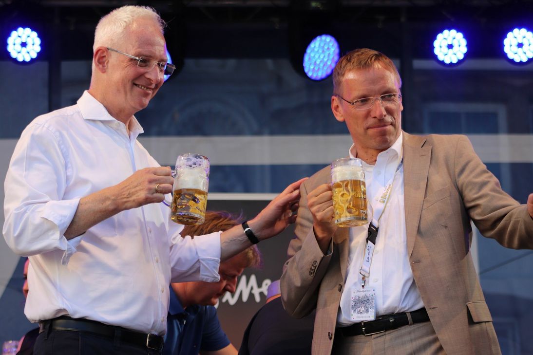 Oberbürgermeister Wolfram Leibe (links) und ttm-Geschäftsführer Norbert Käthler bei der Eröffnung des Altstadtfestes 2019. Die Glaskrüge, die beide in der Hand halten, gehören bald der Vergangenheit an: In diesem Jahr werden Wein und Sekt im neuen Kulturglas, andere alkoholische sowie alle Arten an antialkoholischen Getränken im neu entwickelten Kulturbecher ausgeschenkt. Foto: Trier Tourismus und Marketing GmbH