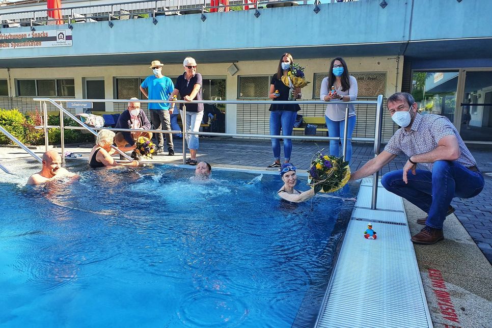Bürgermeister Thomas Jung überreicht den ersten Schwimmerinnen einen Blumenstaruß. Foto. Schmitt