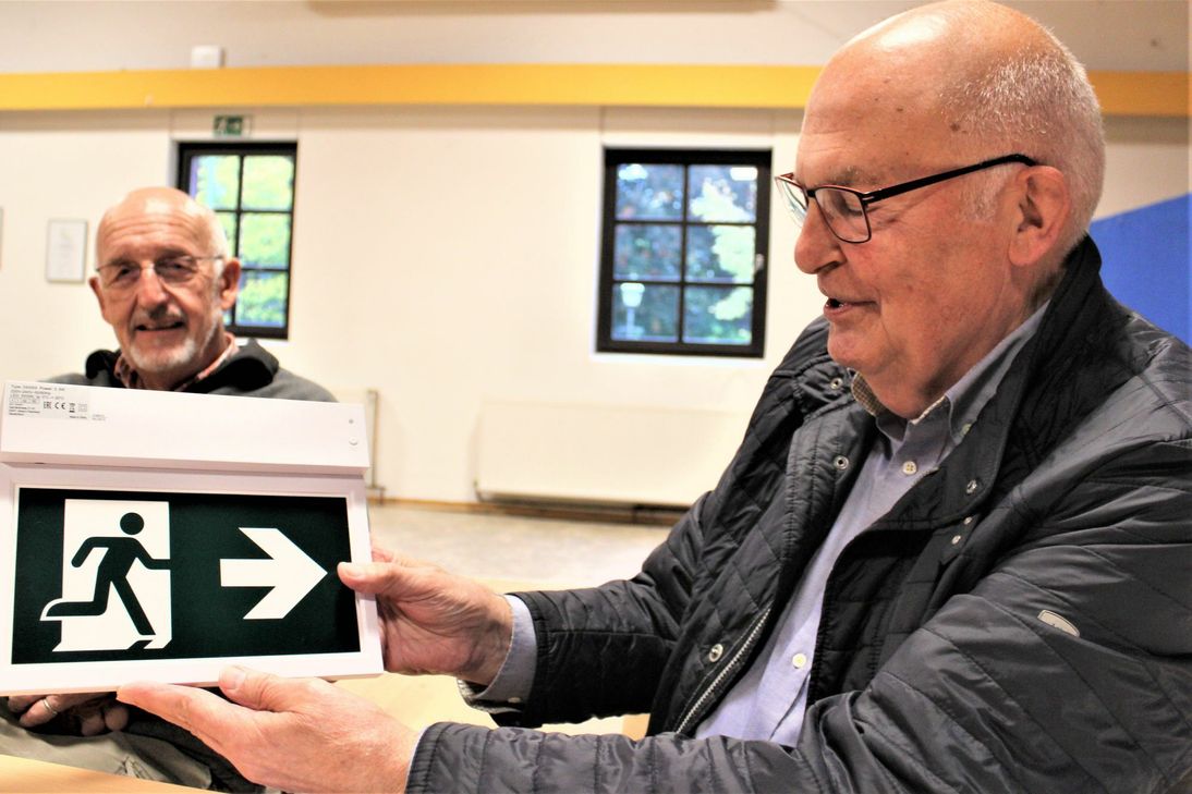 Manfred Adrian (rechts) zeigt Rainer Hülsheger das Hinweisschild zum Notausgang, der eine Schallschutztüre erhalten wird.