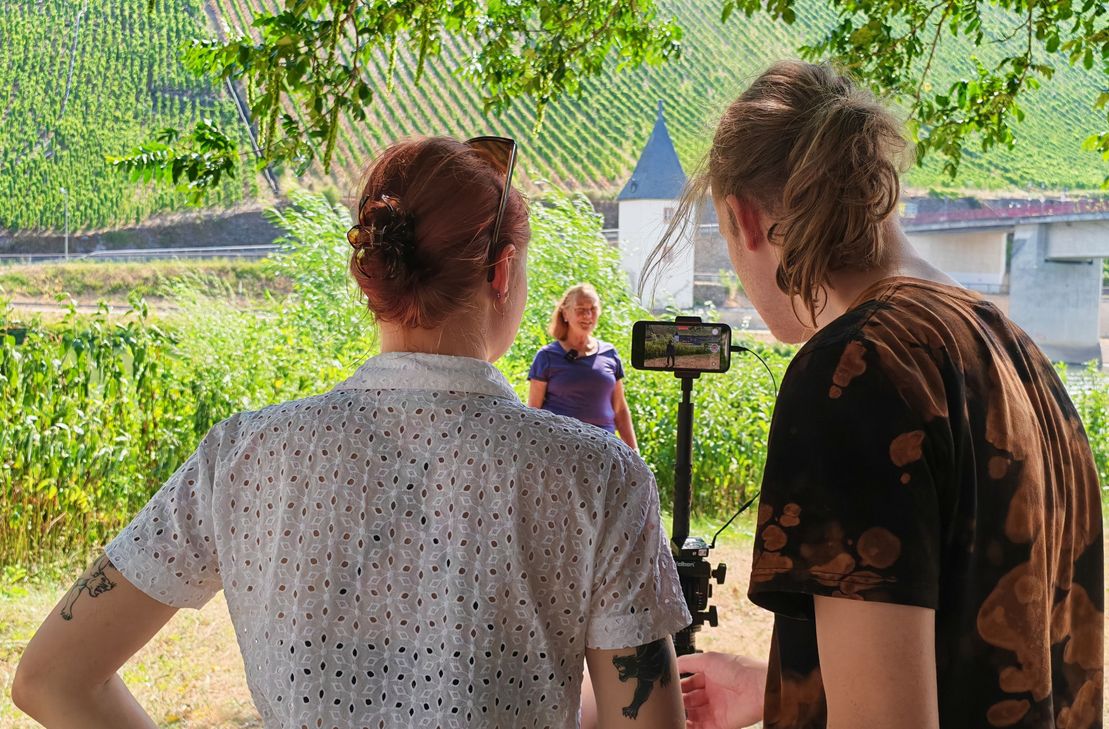 Gästeführerin Marlene Bollig erläutert vor der Kamera die Geschichte der drei Moselbrücken von Trittenheim. Das Filmteam der Universität Koblenz dokumentierte die Aufnahmen für das KuLaDig-Projekt