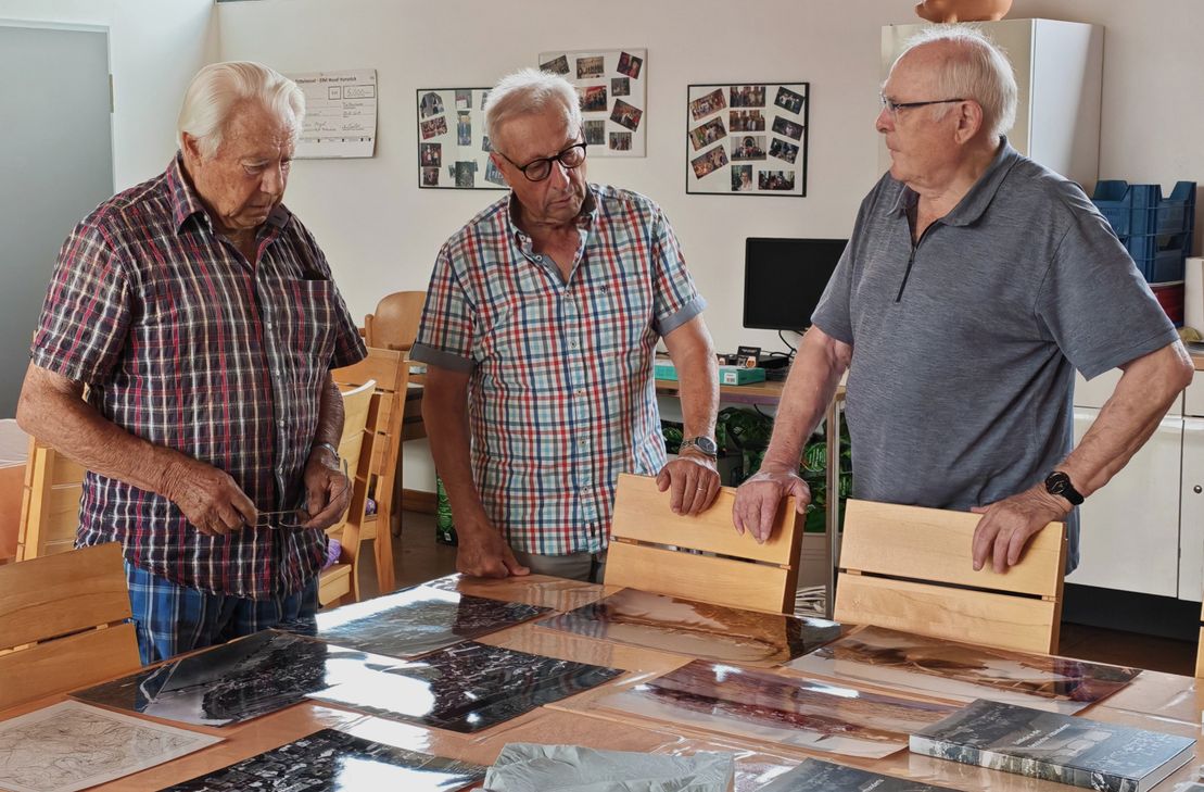 Historische Fotografien und Dokumente regen zum Austausch an: Franz-Josef Schmitt (links), Jürgen Maringer (Mitte) und Alfred Nummer erinnern sich gemeinsam an frühere Zeiten in Trittenheim und ordnen die historischen Aufnahmen ein.