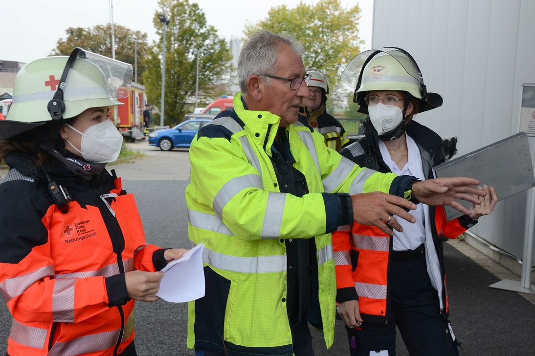 Zwei Einsatzkräfte des DRK im Gespräch mit dem Sicherheitsbeauftragten der gastgebenden Firma Peter Greven Physioderm GmbH.