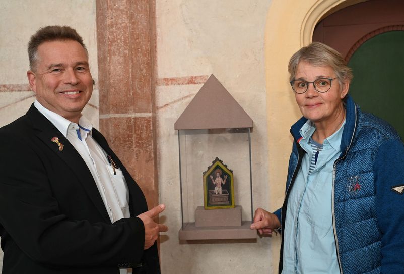 Claudia Müller und Peter Schweikert-Wehner am Hosteler Pax-Täfelchen. Es handelt sich bei diesen früher gebräuchlichen liturgischen Gegenständen um mit Darstellungen Christi, Mariens oder Heiliger verzierte Täfelchen, die zur Weitergabe des Friedenskusses in der Messe dienten.