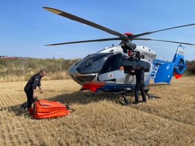 Die Besatzung des Polizeihubschraubers bereitet in Faid den Einsatz vor und befestigt den sogenannten „Bambi Bucket“ – einen Wassersack – am Hubschrauber.