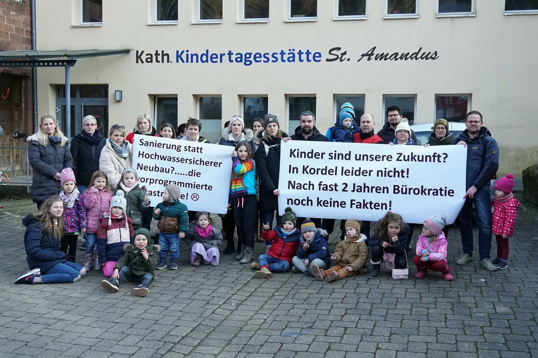 Rund 20 Eltern versammelten sich mit ihren Kindern vor der Hochwasser-Ruine der Kita St. Amandus, um auf ihre missliche Situation aufmerksam zu machen.