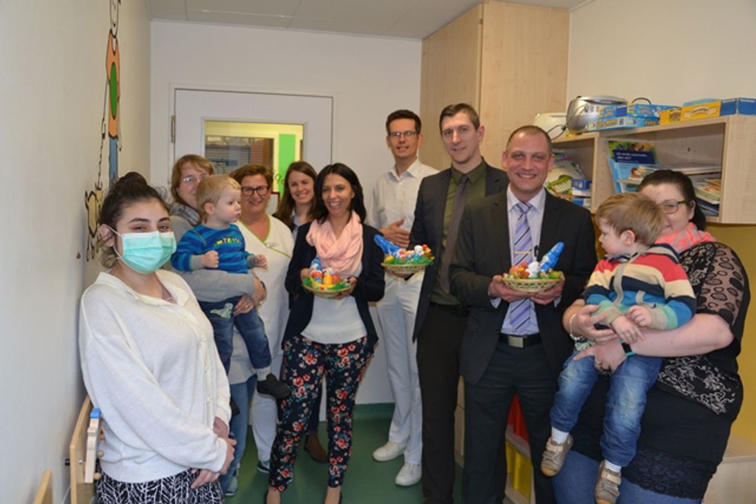 Fröhliche Kinder und Eltern, zufriedene Mitarbeiter aus Edeka-Märkten und Klinikum (v.l.n.r.): Stationsleiterin Andrea Maximini; Pflegedienstleiterin Verena Backendorf; Nicole Willems, Edeka; Dr. Wolfgang Thomas; Sascha Borsch und Benjamin Schug, beide Edeka, mit Patienten und Müttern. Foto: Helga Bohnet