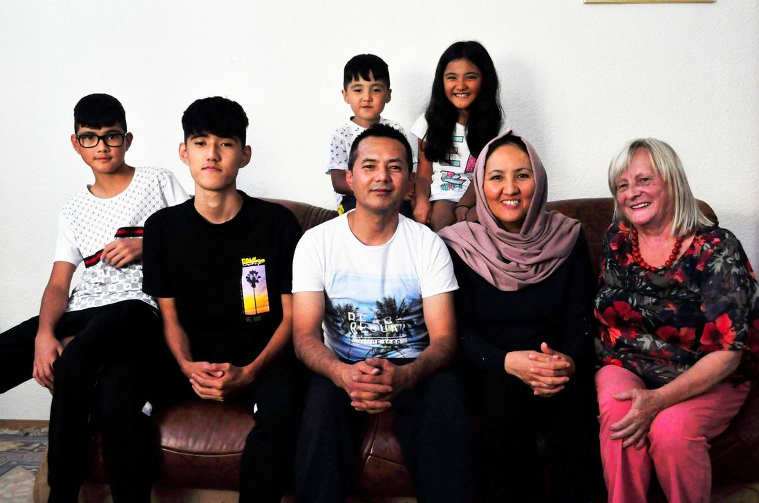 Dem Schrecken der Taliban entkommen: (v.l.) Abu Fassel, Ali, Hayatullah und Sakine - hier auf unserem Foto mit ihrer ehrenamtlichen Unterstützerin Ursula Stimmler. Auf der Sofalehne Nesthäkchen Amir und Narges. Foto: Fischer