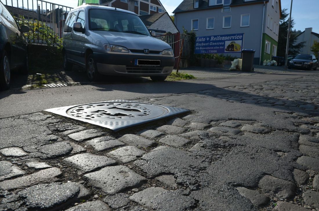 Der untere Abschnitt der Bergstraße (Nähe Güterstraße) ist in einem sehr schlechten Zustand. Hervorstehende Kanaldeckel ...