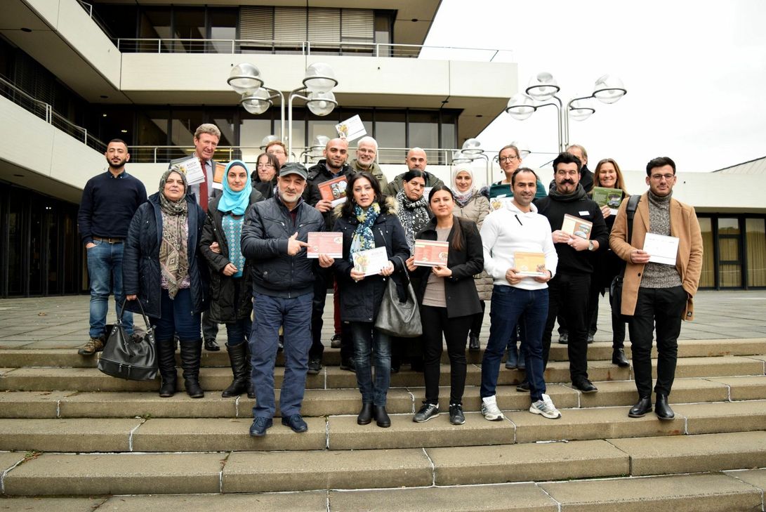 Die ausländischen Hobbyköche- und köchinnen stellten gemeinsam mit Roland Kuhlen ( 3.v.r.) und Judith König (5.v.r.) vom KoBIZ sowie Manfred Poth, Allgemeiner Vertreter des Landrats (3.v.l.), den Koch-Kalender vor. Foto: Breuer