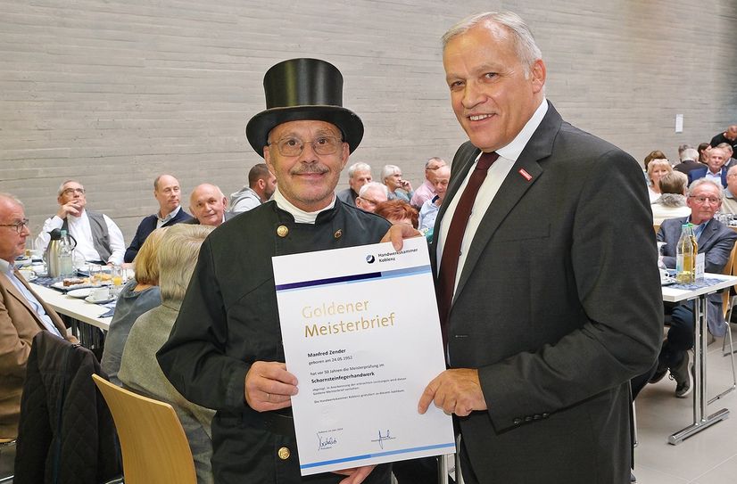 Schornsteinfegermeister Manfred Zender aus Halsenbach (Rhein-Hunsrück-Kreis) kam in seiner zünftigen Berufsbekleidung zur Jubiläumsfeier und erhielt von HwK-Präsident Kurt Krautscheid den Goldenen Meisterbrief.