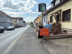 Ortsbürgermeister Edgar Pütmann und Westenergie-Kommunalmanagerin Melanie Dindorf überzeugen sich vor Ort von einer der neu installierten Geschwindigkeitsmesstafeln.
