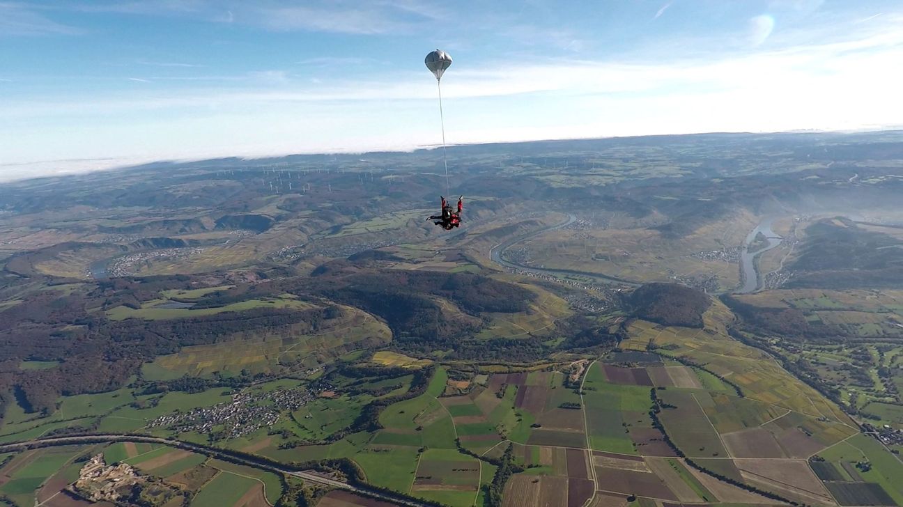 Die Aufnahme zeigt Tandemmaster Christian Neuleib aus Zeltingen-Rachtig mit einem Tandemgast über Föhren. Vorne links liegt Rivenich und im Hintergrund rechts sieht man die Mosel mit der Staustufe in Detzem