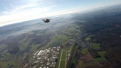 Die Aufnahme zeigt Tandemmaster Christian Neuleib aus Zeltingen-Rachtig mit einem Tandemgast über Föhren. Man erkennt den Flugplatz in Föhren und das angrenzende Industriegebiet. Links sieht man Bekond und rechts Föhren, im Hintergrund liegt Schweich und die Mosel